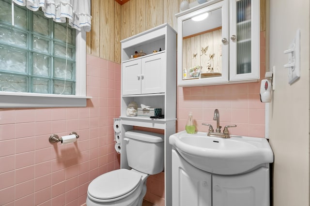 half bath with tile walls, toilet, decorative backsplash, and vanity