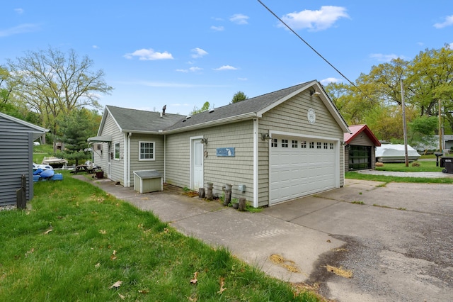 view of side of home featuring a detached garage and a shingled roof