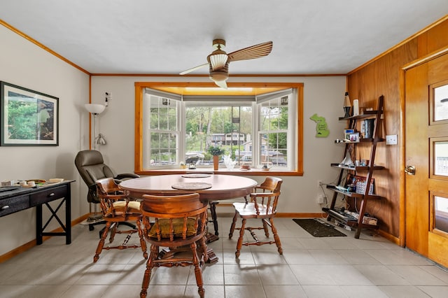 dining space featuring ornamental molding, a ceiling fan, wood walls, and baseboards