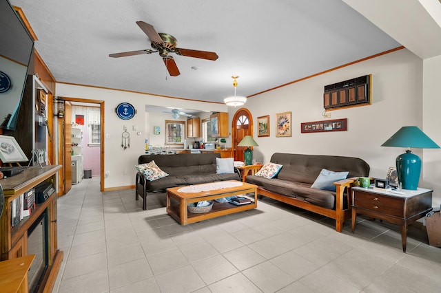 living area with a ceiling fan, ornamental molding, light tile patterned flooring, and baseboards