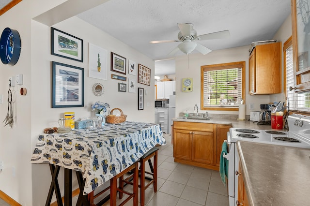 kitchen with electric range, stainless steel microwave, plenty of natural light, a ceiling fan, and a textured ceiling