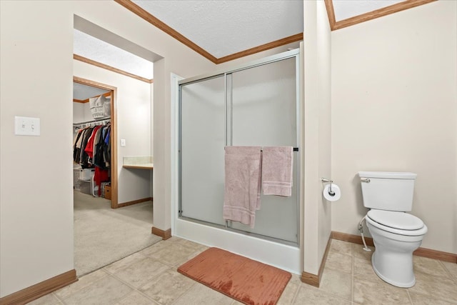 bathroom featuring ornamental molding, a shower stall, baseboards, toilet, and a textured ceiling