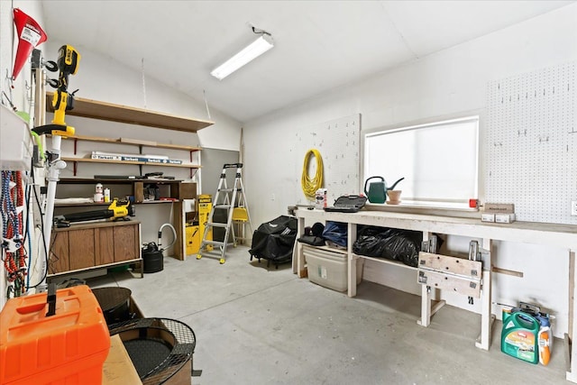 miscellaneous room featuring a workshop area, unfinished concrete floors, and lofted ceiling