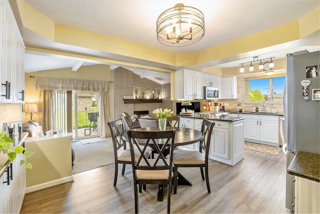 dining area featuring a chandelier, light wood finished floors, healthy amount of natural light, and a fireplace