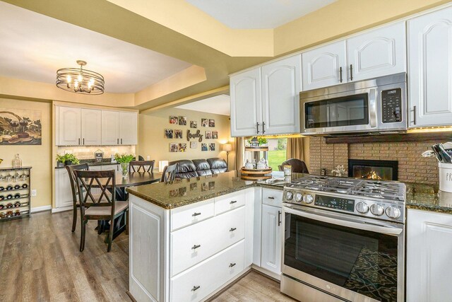 kitchen with appliances with stainless steel finishes, a peninsula, and white cabinetry