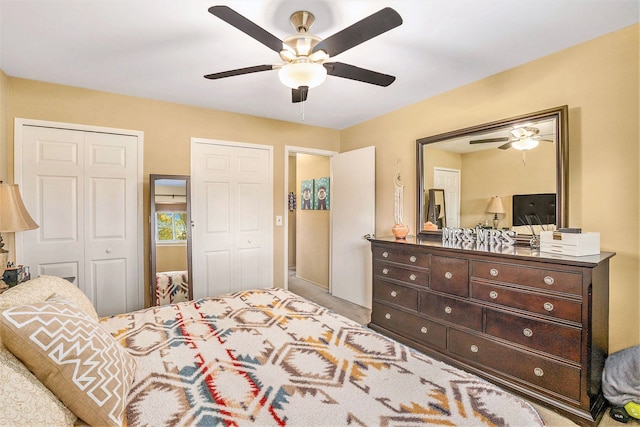 carpeted bedroom with two closets and ceiling fan