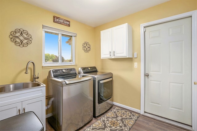 laundry area featuring separate washer and dryer, cabinet space, wood finished floors, and baseboards