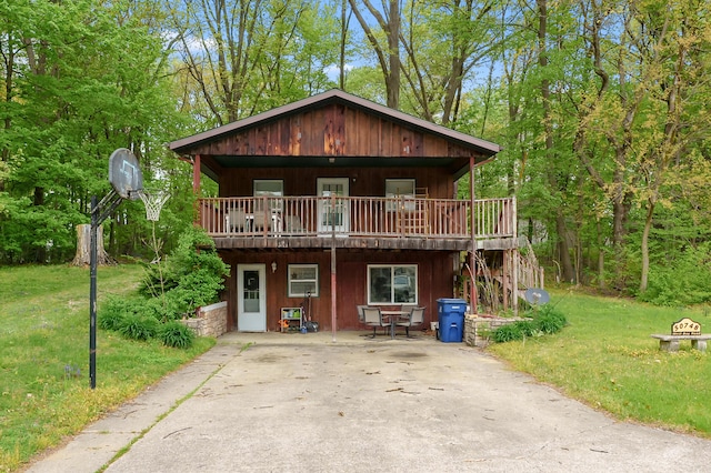 chalet / cabin with a deck, a front yard, and a patio area