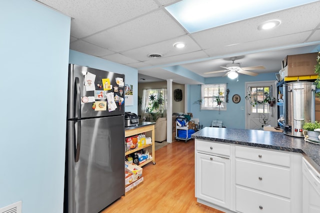 kitchen with freestanding refrigerator, a ceiling fan, a peninsula, dark countertops, and white cabinetry