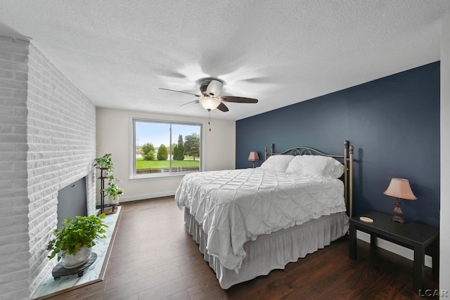 608 Budlong St, Adrian, MI 49221 - bedroom with dark wood-type flooring, a textured ceiling, ceiling fan, a fireplace, and baseboards