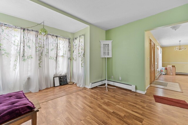 512 Kalkaska Rd NW, Kalkaska, MI 49646 - unfurnished room with a baseboard radiator, a chandelier, wood finished floors, a baseboard heating unit, and baseboards