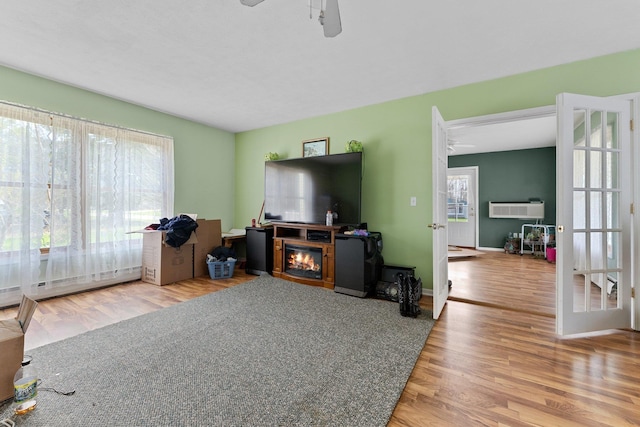 512 Kalkaska Rd NW, Kalkaska, MI 49646 - living area with a ceiling fan, wood finished floors, a wall unit AC, a glass covered fireplace, and french doors