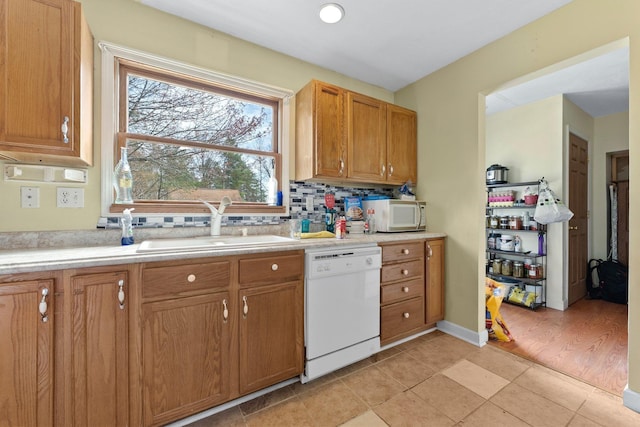 512 Kalkaska Rd NW, Kalkaska, MI 49646 - kitchen with white appliances, a sink, light countertops, backsplash, and brown cabinetry