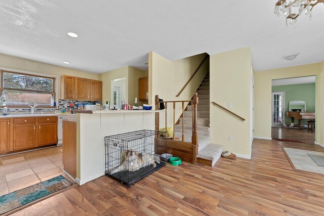 512 Kalkaska Rd NW, Kalkaska, MI 49646 - kitchen featuring light wood-style floors, a sink, light countertops, brown cabinetry, and backsplash