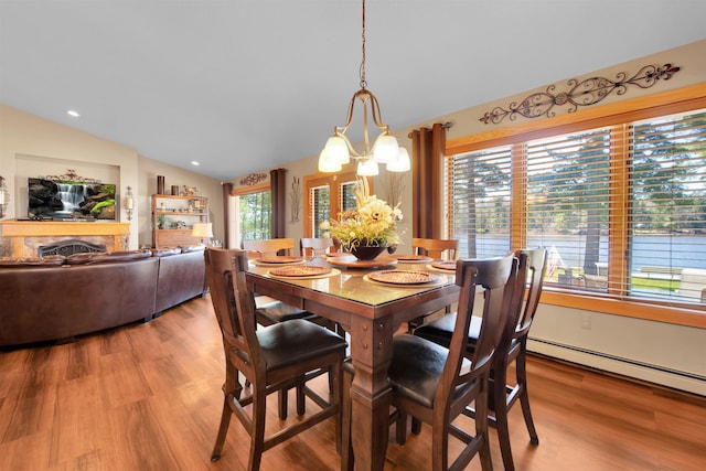 7017 Loud Dr, Oscoda, MI 48750 - dining room featuring a chandelier, wood finished floors, vaulted ceiling, a baseboard radiator, and recessed lighting