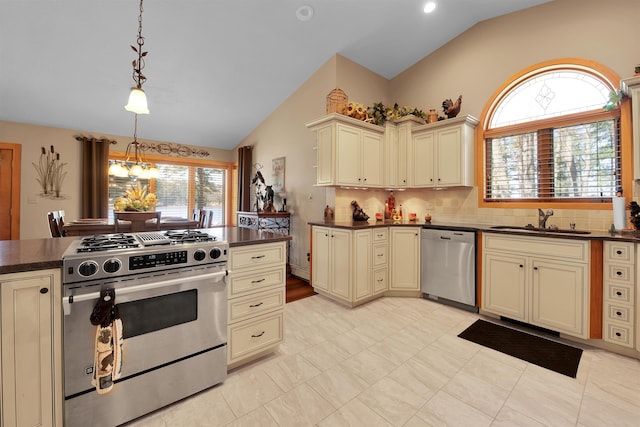7017 Loud Dr, Oscoda, MI 48750 - kitchen featuring stainless steel appliances, cream cabinetry, lofted ceiling, a sink, and dark countertops