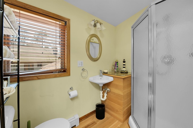 7017 Loud Dr, Oscoda, MI 48750 - full bath featuring baseboard heating, toilet, a stall shower, baseboards, and wood finished floors