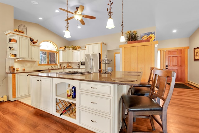 7017 Loud Dr, Oscoda, MI 48750 - kitchen with open shelves, stainless steel appliances, light wood finished floors, ceiling fan, and vaulted ceiling