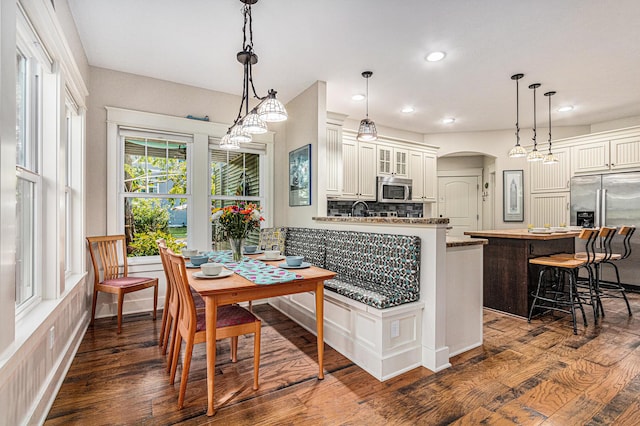 7251 E Beach Dr, South Haven, MI 49090 - kitchen with stainless steel appliances, a breakfast bar, dark wood-style flooring, recessed lighting, and glass insert cabinets