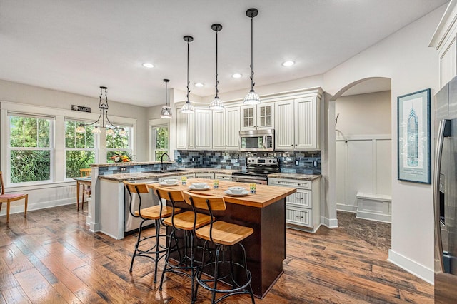 7251 E Beach Dr, South Haven, MI 49090 - kitchen with stainless steel appliances, wood counters, a peninsula, a sink, and a breakfast bar area