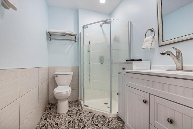 7251 E Beach Dr, South Haven, MI 49090 - bathroom featuring a stall shower, toilet, vanity, tile patterned flooring, and tile walls