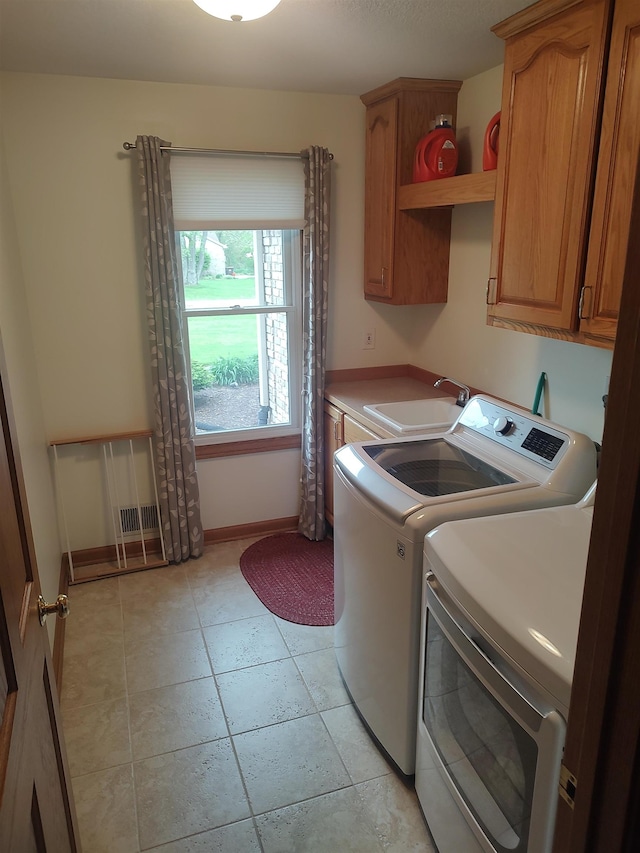 washroom featuring cabinet space, washing machine and clothes dryer, baseboards, and light tile patterned flooring
