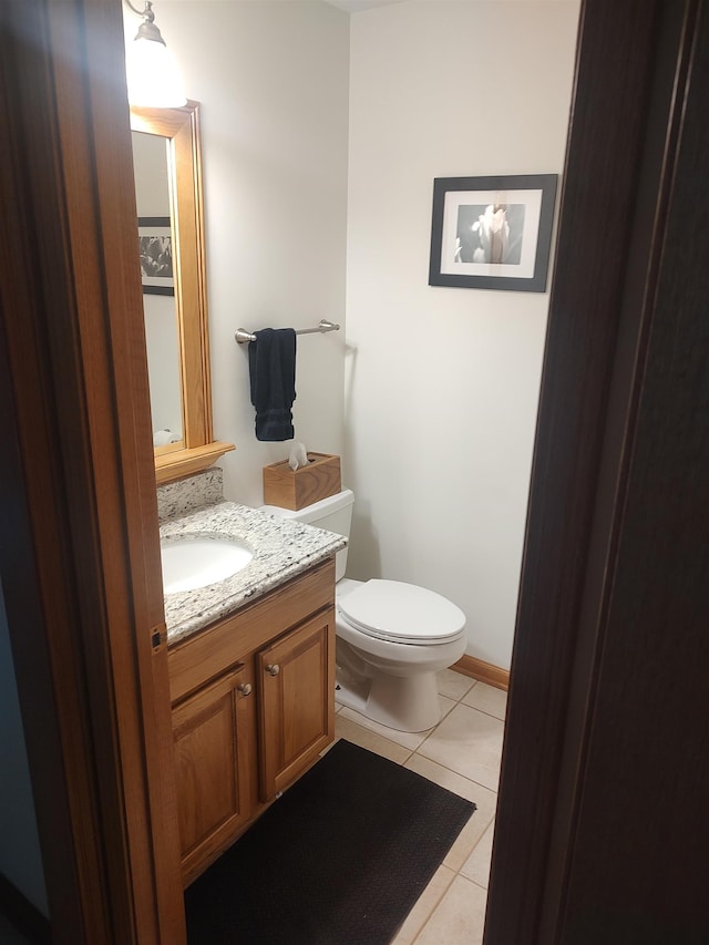 half bathroom with tile patterned flooring, toilet, and vanity