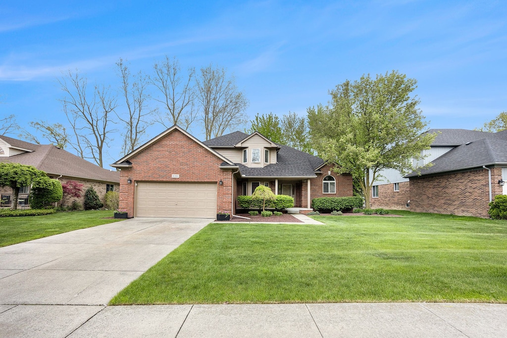31390 Rowland Ln, Chesterfield, MI 48051 - traditional home with a garage, brick siding, a front yard, driveway, and a shingled roof