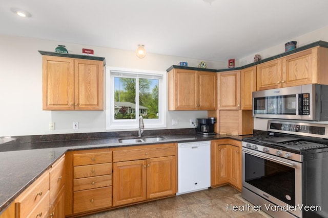 kitchen featuring stainless steel appliances, a sink, and dark stone countertops