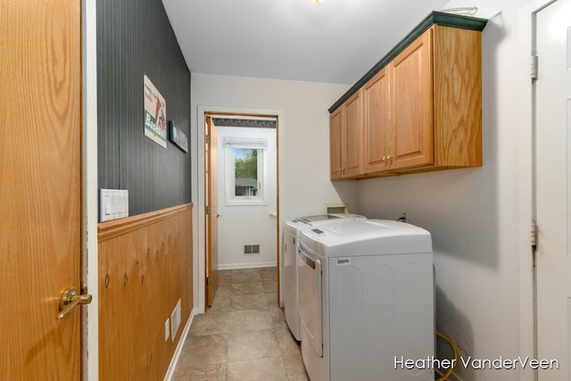 laundry room featuring washer and clothes dryer, cabinet space, baseboards, and stone finish floors