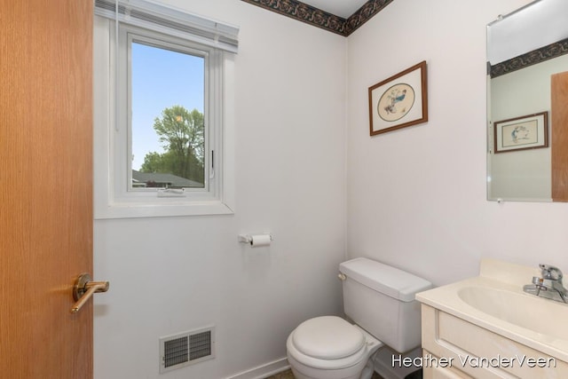 bathroom with toilet, vanity, and baseboards