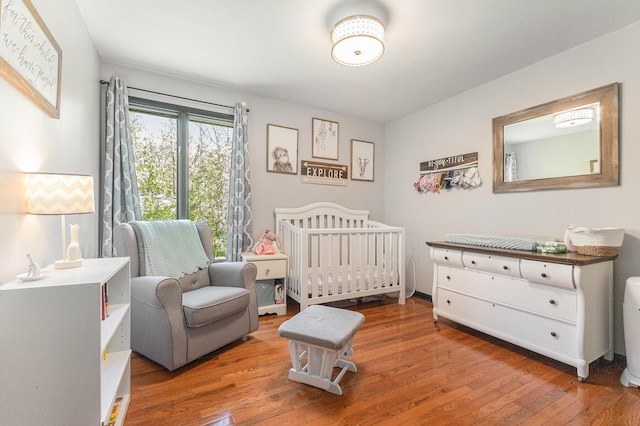 bedroom with wood finished floors and a crib