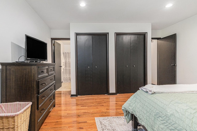 bedroom with light wood-style flooring, two closets, recessed lighting, and ensuite bathroom