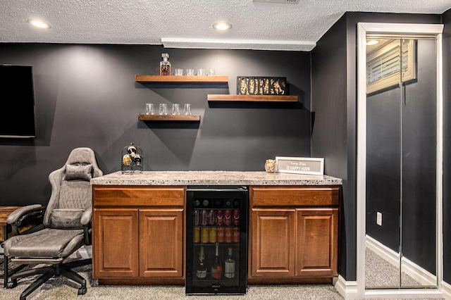 indoor dry bar featuring beverage cooler, light carpet, and a textured ceiling