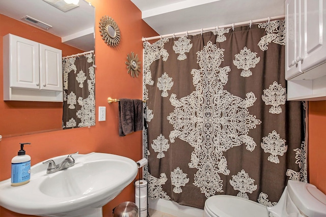 bathroom with toilet, a sink, and a shower with curtain