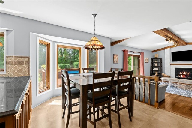 6588 White Pines Dr, Brighton, MI 48116 - dining area featuring plenty of natural light, a glass covered fireplace, beam ceiling, track lighting, and a chandelier