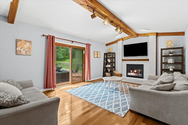 6588 White Pines Dr, Brighton, MI 48116 - living area featuring rail lighting, wood finished floors, a brick fireplace, and baseboards