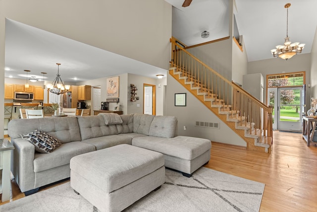 living area featuring a chandelier, a high ceiling, light wood-type flooring, and stairway