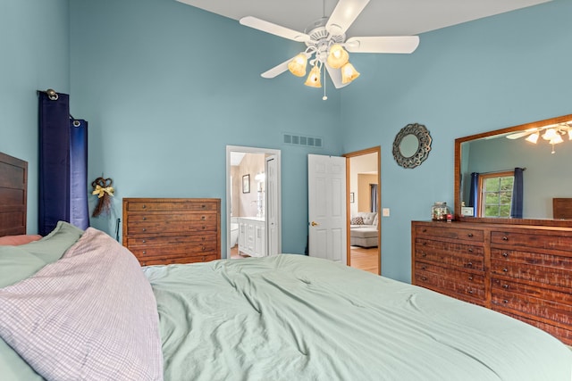 bedroom with a high ceiling, ensuite bath, and a ceiling fan