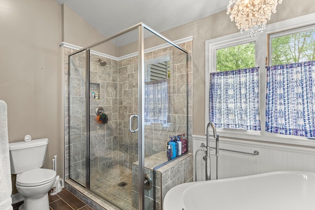 bathroom with a bath, a shower stall, toilet, a chandelier, and a wainscoted wall