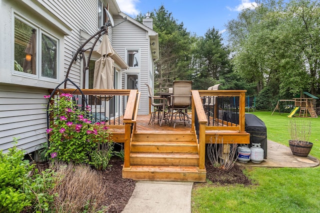 wooden terrace with a yard, outdoor dining area, and a playground