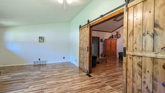 7884 N Saint Helen Rd, Saint Helen, MI 48656 - spare room featuring a barn door, wood finished floors, baseboards, and lofted ceiling