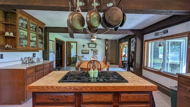 7884 N Saint Helen Rd, Saint Helen, MI 48656 - kitchen with black gas cooktop, light tile patterned floors, light countertops, open shelves, and brown cabinetry