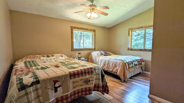 7884 N Saint Helen Rd, Saint Helen, MI 48656 - bedroom with lofted ceiling, wood finished floors, baseboards, a ceiling fan, and a textured ceiling