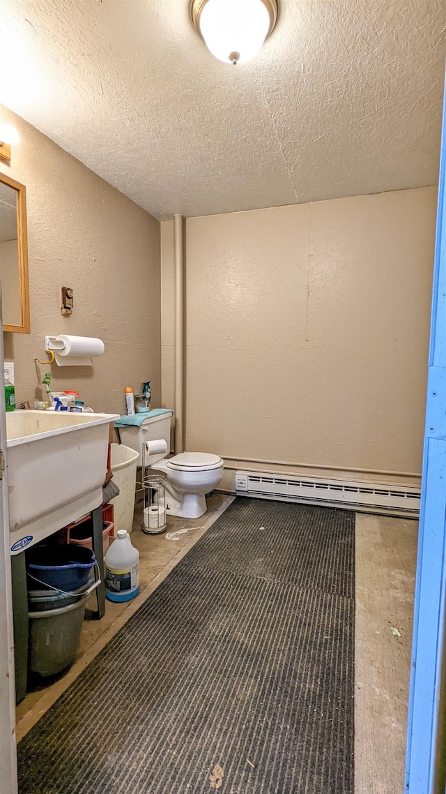 7884 N Saint Helen Rd, Saint Helen, MI 48656 - bathroom with a textured wall, toilet, a textured ceiling, and a baseboard heating unit