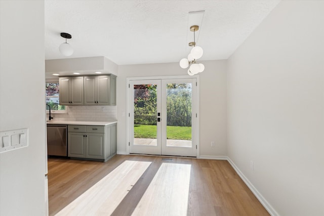5082 Patland Dr, Kalamazoo, MI 49009 - kitchen with gray cabinets, stainless steel dishwasher, light wood finished floors, french doors, and decorative backsplash