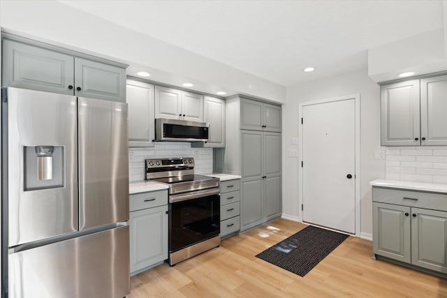 5082 Patland Dr, Kalamazoo, MI 49009 - kitchen with appliances with stainless steel finishes, gray cabinets, light wood-style floors, light countertops, and decorative backsplash