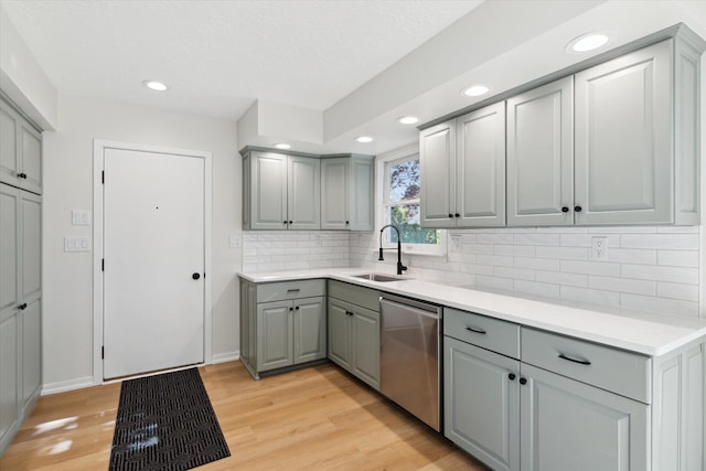 5082 Patland Dr, Kalamazoo, MI 49009 - kitchen with gray cabinetry, a sink, stainless steel dishwasher, light wood-style floors, and backsplash