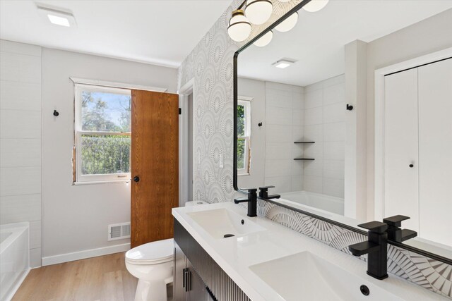 5082 Patland Dr, Kalamazoo, MI 49009 - bathroom with wood finished floors, toilet, baseboards, and double vanity
