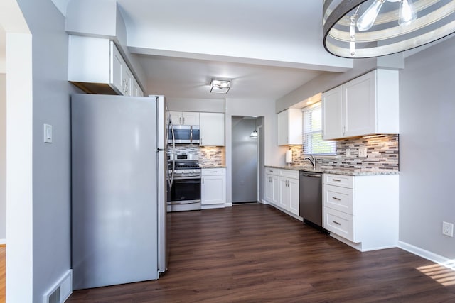 kitchen with stainless steel appliances, backsplash, dark wood-style floors, white cabinetry, and light stone counters